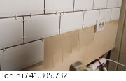 Male Worker Master Laying Ceramic Tiles on the Wall of Kitchen. Repairman Placing White Modern Tiles, Spreading Adhesive. Builder Installing Tile at Repair Renovation Work. Professional Tiling. 4K. Стоковое видео, видеограф Марина Демидюк / Фотобанк Лори