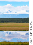 Beautiful landscape of foothill valley in early autumn. On rocky mountains there are low cumulus clouds, behind river with reflection of mountain there is yellowed meadow. Natural background. Стоковое фото, фотограф Виктория Катьянова / Фотобанк Лори