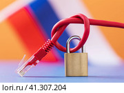 Закрытый замок на завязанном сетевом проводе на фоне Российского флага, концепция на тебу блокирования интернет ресурсов в России. Стоковое фото, фотограф Сергей Чайко / Фотобанк Лори