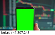 Black phone with blank mockup screen on rising stock graph. Closeup hand showing smartphone isolated green display. Online banking, Fund App use. Financial analyst on Invest Market. Bank collapse 2023. Стоковое видео, видеограф Марина Демидюк / Фотобанк Лори