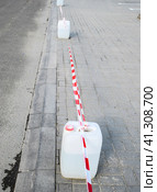 Canisters of water exposed as temporary barriers. The prohibitive tape. Стоковое фото, фотограф Леонид Еремейчук / Фотобанк Лори