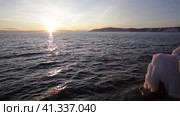 Video of Baikal Lake at sunset in December. Waves crash against an icy pier against the backdrop of the setting sun. Beautiful seascape. Natural background. Travels along the lake shore. Стоковое видео, видеограф Виктория Катьянова / Фотобанк Лори