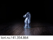 Черный конь. Шахматная фигура на столе освещенная в темноте. Стоковое фото, фотограф Роман Сибиряков / Фотобанк Лори