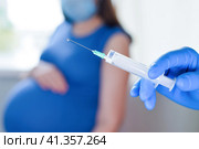 Pregnant Vaccination. Pregnant Woman In Face Mask Getting Vaccinated in Clinic. Doctor Giving Corona Virus Vaccine Injection Patient. Covid-19 Flu Protection. Selective focus. Syringe close up. Стоковое фото, фотограф Марина Демидюк / Фотобанк Лори