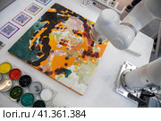 Робот-художник рисует картину красками на холсте на 11-й международной ярмарке современного искусства Cosmoscow в городе Москве, Россия (2023 год). Редакционное фото, фотограф Николай Винокуров / Фотобанк Лори
