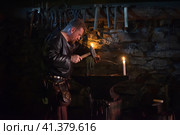 Russia, St. Petersburg 28,12,2016 Blacksmith in a medieval forge at the medieval festival "Days of History" (2015 год). Редакционное фото, фотограф Анна Кривицкая / Фотобанк Лори