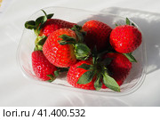 Ripe strawberries in a plastic package on a white background. Delicious fresh berries in a container for sale to customers. Keeping food fresh. Healthy food, vitamins and microelements. Стоковое фото, фотограф Юлия Петровская / Фотобанк Лори