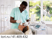 African American cosmetologist performing facial cryotherapy procedure on man. Стоковое фото, фотограф Яков Филимонов / Фотобанк Лори