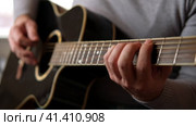 Playing the guitar. Strumming acoustic guitar. Musician plays music. Man fingers holding mediator. Man hand playing guitar neck in dark room. Unrecognizable person rehearsing, fretboard close-up. Стоковое видео, видеограф Марина Демидюк / Фотобанк Лори