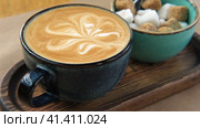 Blue Ceramic Cup of Hot Cappuccino with Flower Shaped Foam on Wooden Cafe Table. Beautiful Latte Art Froth. Trendy Authentic Modern Porcelain Set. Pottery Handmade Coffee Mug Served with a Sugar Bowl. Стоковое видео, видеограф Марина Демидюк / Фотобанк Лори