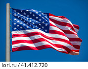 American flag waving in the wind against blue sky. Стоковое фото, фотограф Nobilior / Фотобанк Лори