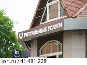 Inscription in the Russian laguage on the funeral home. Translation - funeral services. Business that provides burial and funeral services for the dead and their families (2022 год). Редакционное фото, фотограф YuryKara / Фотобанк Лори