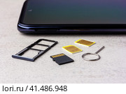 Smartphone and open slots for nano SIM cards, two nano SIM cards, micro SD drive and metal key on grey background close up. Стоковое фото, фотограф Андрей С / Фотобанк Лори