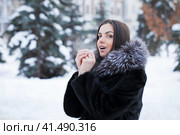 Young woman warms her palms with her breath in the frosty weather of her palms. Стоковое фото, фотограф Андрей Аркуша / Фотобанк Лори