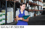 In warehouse of store, girl checks quantity of goods and receipt documents for products. Стоковое видео, видеограф Яков Филимонов / Фотобанк Лори