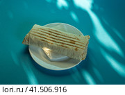 Large shawarma on a white plate with a napkin on a blue background with shadows. Food, healthy fast food, delicious to eat. Стоковое фото, фотограф Tae Mi / Фотобанк Лори