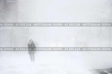 Пурга в городе. Мужчина во время метели идет по улице. Автомобили на заснеженной дороге. Сильный ветер и снегопад. Снежный шторм в Арктике. Ухудшение погоды и плохая видимость. Суровый климат в Сибири и на Крайнем Севере России. Анадырь, Чукотка, Дальний Восток России. Стоковое фото, фотограф Андрей Степанов / Фотобанк Лори