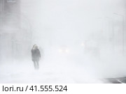 Пурга в городе. Мужчина во время метели идет по улице. Автомобили на заснеженной дороге. Сильный ветер и снегопад. Снежный шторм в Арктике. Ухудшение погоды и плохая видимость. Суровый климат в Сибири и на Крайнем Севере России. Анадырь, Чукотка, Дальний Восток России. Стоковое фото, фотограф Андрей Степанов / Фотобанк Лори