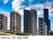 Facades of new residential buildings on Mukomolnyy Proyezd, 2 and blue sky with white clouds. Modern multi-storey residential houses in Moscow (2022 год). Редакционное фото, фотограф Константин Григорьев / Фотобанк Лори