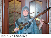 A man dressed up in a knight's hauberk at home in his room. Knight's sword in the hands of a man. Стоковое фото, фотограф Леонид Еремейчук / Фотобанк Лори