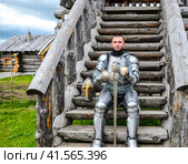 Knight in the armor on the wooden steps. Knightly armor and weapon. Стоковое фото, фотограф Леонид Еремейчук / Фотобанк Лори