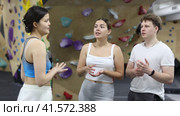 Asian girl, European woman and teenage guy - group of friends stand actively relaxing in climb hall. Стоковое видео, видеограф Яков Филимонов / Фотобанк Лори