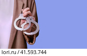 Woman teacher holding handcuffs in her hands on a blue background, banner close-up. Стоковое фото, фотограф Андрей Журавлев / Фотобанк Лори