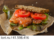 Redfish bread snack with salad and tomatoes laying on a kraft paper. Стоковое фото, фотограф Воловодов Владимир / Фотобанк Лори