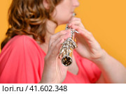 Portrait of a woman musician with a flute on a studio yellow background. Flutist with a large concert transverse flute in her hands. Стоковое фото, фотограф Андрей Журавлев / Фотобанк Лори
