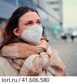 Young woman with curly hair in face mask with ffp2 respirator on a city street, outdoor. Стоковое фото, фотограф Андрей Журавлев / Фотобанк Лори