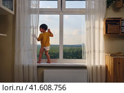 The child is alone by the window, lost in thought and risking their safety. Kid aged two years. Стоковое фото, фотограф Андрей Журавлев / Фотобанк Лори