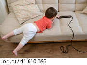 Baby plays dangerously with hair curling tongs, risking burns or injuries. Child's curiosity and lack of awareness pose a serious threat to their safety. Kid aged about two years (one year ten months) Стоковое фото, фотограф Андрей Журавлев / Фотобанк Лори