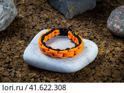 Braided paracord bracelet on the background of stones. Handmade, creative design. Стоковое фото, фотограф Артем Лукин / Фотобанк Лори