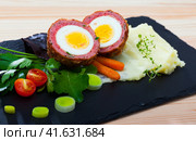 Dishes of traditional Scottish cuisine of scotch egg served with greens and potatoes. Стоковое фото, фотограф Яков Филимонов / Фотобанк Лори