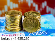 Монеты на двухтысячной купюре на не резком фоне графика курса валют (2023 год). Редакционное фото, фотограф Анна Аникова / Фотобанк Лори