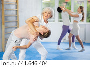Senior woman applying inverted headlock during mock bout in self-defense training. Стоковое фото, фотограф Яков Филимонов / Фотобанк Лори
