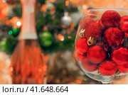 red glitter balls in a large wine glass close up against the background of a decorated Christmas tree. Стоковое фото, фотограф Артем Курутин / Фотобанк Лори