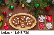 Merry Christmas and Happy New Year. Video of homemade Christmas cookies in shape of X-mas trees and hearts in wooden plate and fresh tangerines. Christmas tree branches, New Year toys on wood table. Стоковое видео, видеограф Виктория Катьянова / Фотобанк Лори