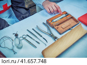 Ancient hospital for treatment soldiers on battlefield - 18th or 19th century. Forceps, syringe, scissors, scalpel and other medical instruments on the table. Medicine in a field military hospital. (2019 год). Редакционное фото, фотограф Андрей Журавлев / Фотобанк Лори