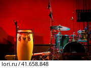 Traditional ethnic Cuban conga drum and modern drum set on red background. Percussion instruments at a jazz concert. Ethnic african Djembe at a concert of jazz music. Стоковое фото, фотограф Андрей Журавлев / Фотобанк Лори