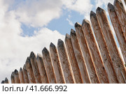 Клязьминский городок (Стародуб), Владимирская область, Россия. Август 2023 года. Фрагмент забора из деревянных кольев на фоне голубого неба с облаками. Стоковое фото, фотограф Сергей Никифоров-Гордеев / Фотобанк Лори