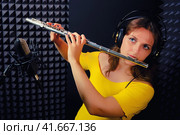 Woman flutist plays Boehm flute, black background. Female flute player playing in music studio. Record wind musical instruments with a professional microphone. Стоковое фото, фотограф Андрей Журавлев / Фотобанк Лори