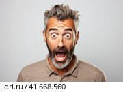 A young handsome man with a beard in a casual sweater on a gray background is afraid and shocked by surprise. Generated by AI. Стоковое AI-изображение, AI-художник Ярославский Максим / Фотобанк Лори