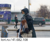Moscow, Russia - November 25, 2020: Still life. Sretenka Street during coronavirus pandemic. Aged lady wear, put on, use protective face mask. Portrait of citizen. Редакционное фото, фотограф YuryKara / Фотобанк Лори