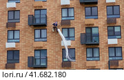 An industrial climber insulates the facade of a residential building with insulation. Стоковое видео, видеограф Андрей Журавлев / Фотобанк Лори