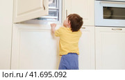 Baby takes a risk and opens the freezer door to grab some food. Always make sure to close the fridge door properly to avoid any accidents. Kid aged about two years (one year ten months) Стоковое видео, видеограф Андрей Журавлев / Фотобанк Лори