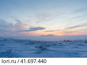 Закат в тундре. Ранние зимние сумерки. Холодная морозная зимняя погода. Зимний арктический пейзаж. Электрические столбы и спутниковые тарелки в заснеженной тундре. Чукотка, Сибирь, Дальний Восток России, Арктика. Стоковое фото, фотограф Андрей Степанов / Фотобанк Лори