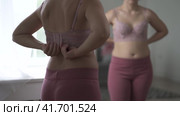 A woman tries on a bra in the fitting room, a bustier with a wide clasp is reflected in the mirror. Стоковое видео, видеограф Станислав Тарко / Фотобанк Лори