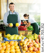 Male seller of vegetable department of store replenishing showcase with apple, put ones on showcase. Стоковое фото, фотограф Яков Филимонов / Фотобанк Лори