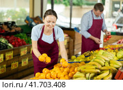 Woman selelr of vegetable department store is replenishing showcase with oranges. Стоковое фото, фотограф Яков Филимонов / Фотобанк Лори